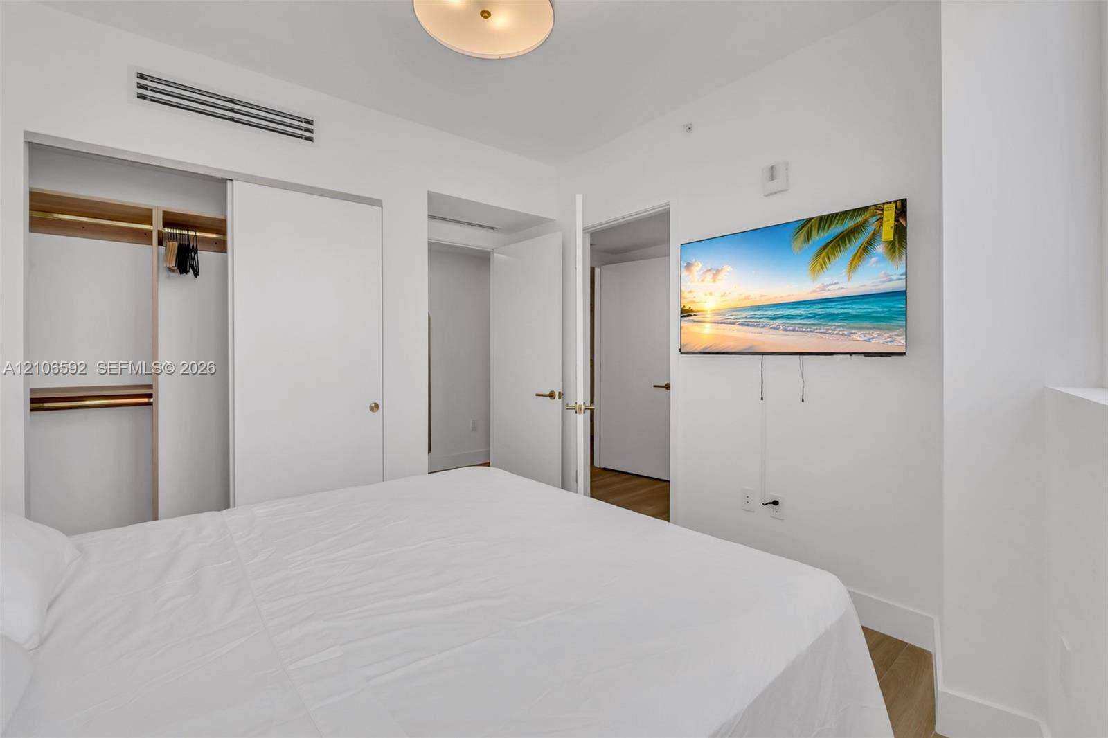 90 NE 32, #612, Miami, Miami, FL 33127 Room featuring wood-finish flooring, ceiling-mounted light fixture, sliding door closet with built-in shelving, and integrated climate control unit