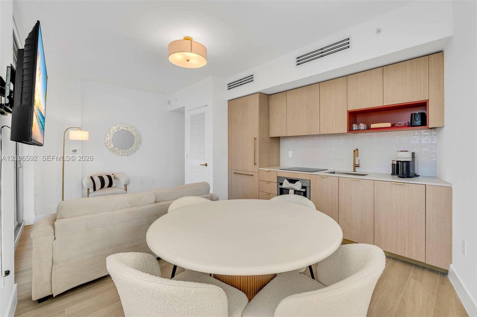 90 NE 32, #612, Miami, Miami, FL 33127 Kitchen featuring light wood-finish cabinetry, a contrasting red open shelf, an integrated cooktop, a built-in oven, and a gold-tone faucet, complemented by wood-finish flooring and a central drum-style pendant light