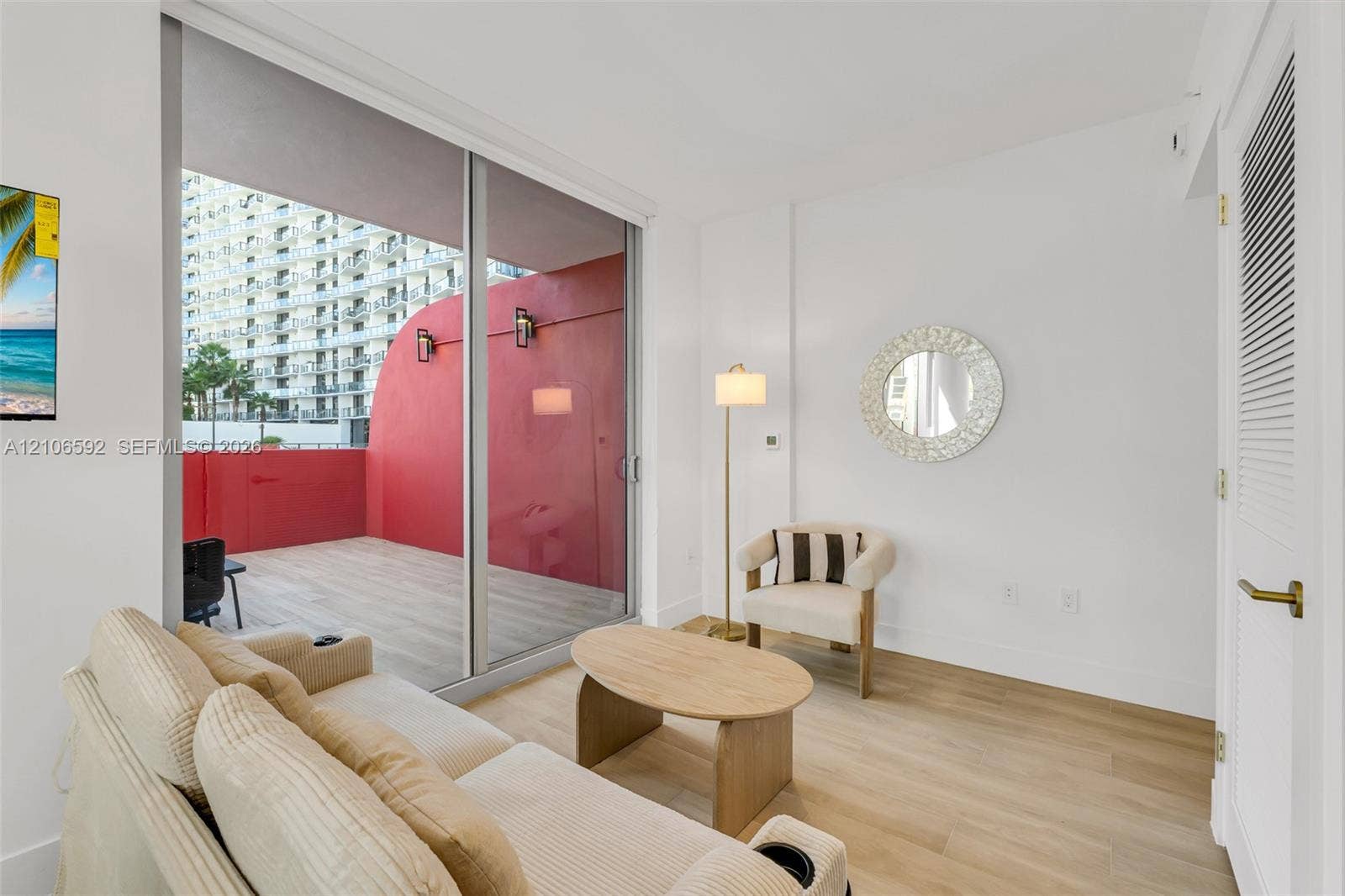90 NE 32, #612, Miami, Miami, FL 33127 Sliding glass door opening to a private balcony with wood-finish decking, wall-mounted exterior light fixtures, and neutral wood-finish flooring throughout the interior