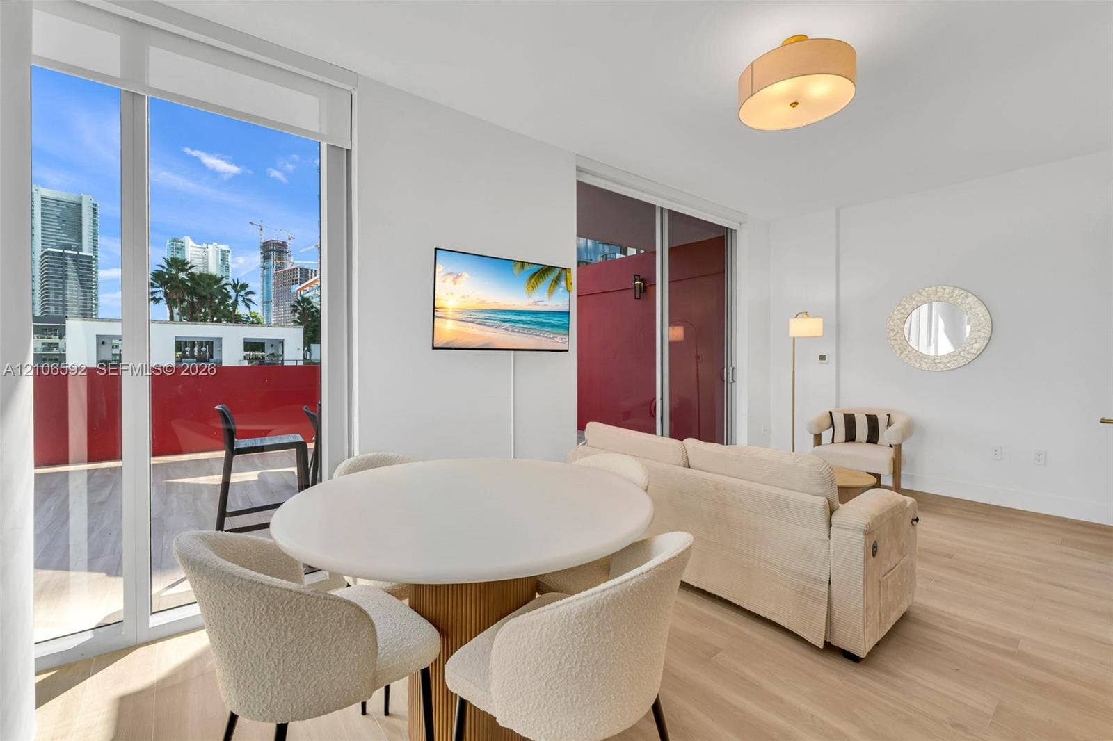 90 NE 32, #612, Miami, Miami, FL 33127 Floor-to-ceiling sliding glass doors, light wood-finish flooring, recessed drum lighting, and expansive private balcony with red-toned exterior walls