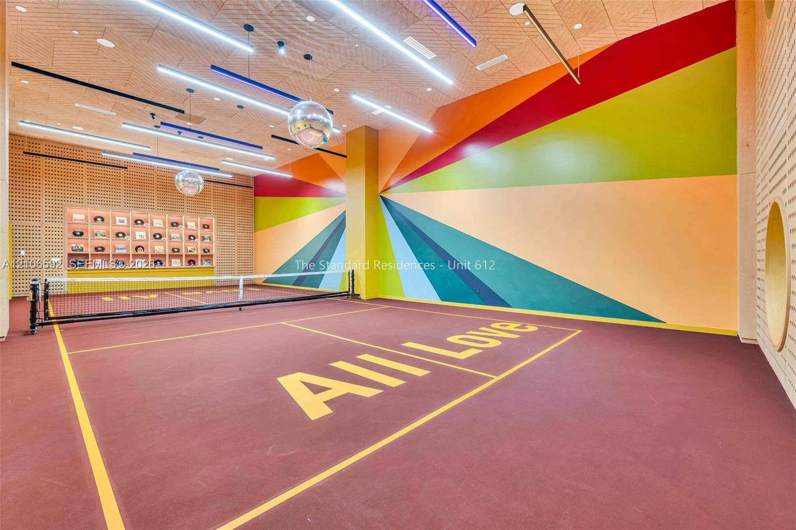 90 NE 32, #612, Miami, Miami, FL 33127 Indoor pickleball court featuring a specialized athletic surface, built-in display shelving, linear LED lighting, and decorative wall mural