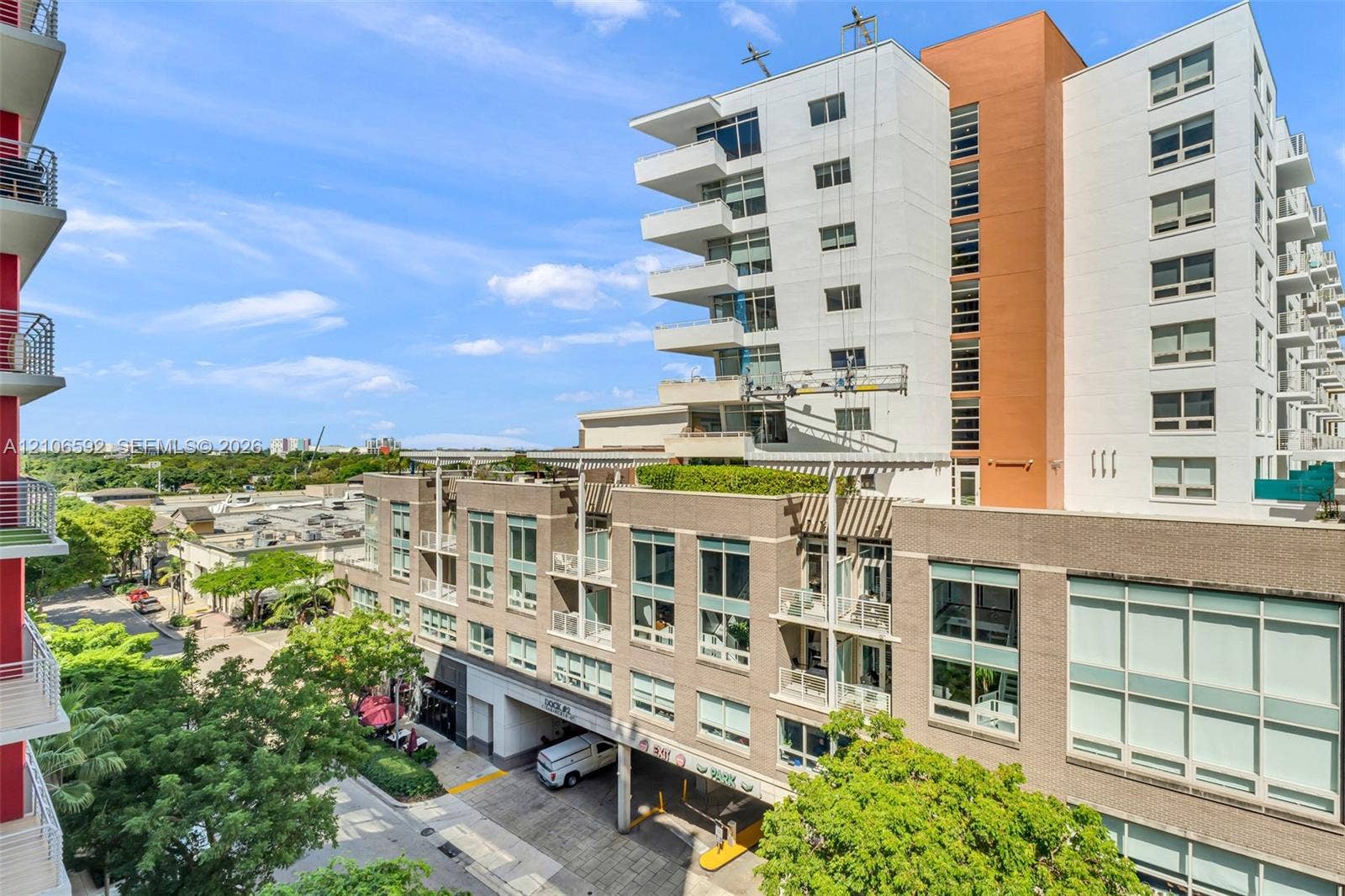 90 NE 32, #612, Miami, Miami, FL 33127 Mid-rise building exterior featuring a textured masonry facade, extensive floor-to-ceiling windows, private balconies, and an integrated structural trellis