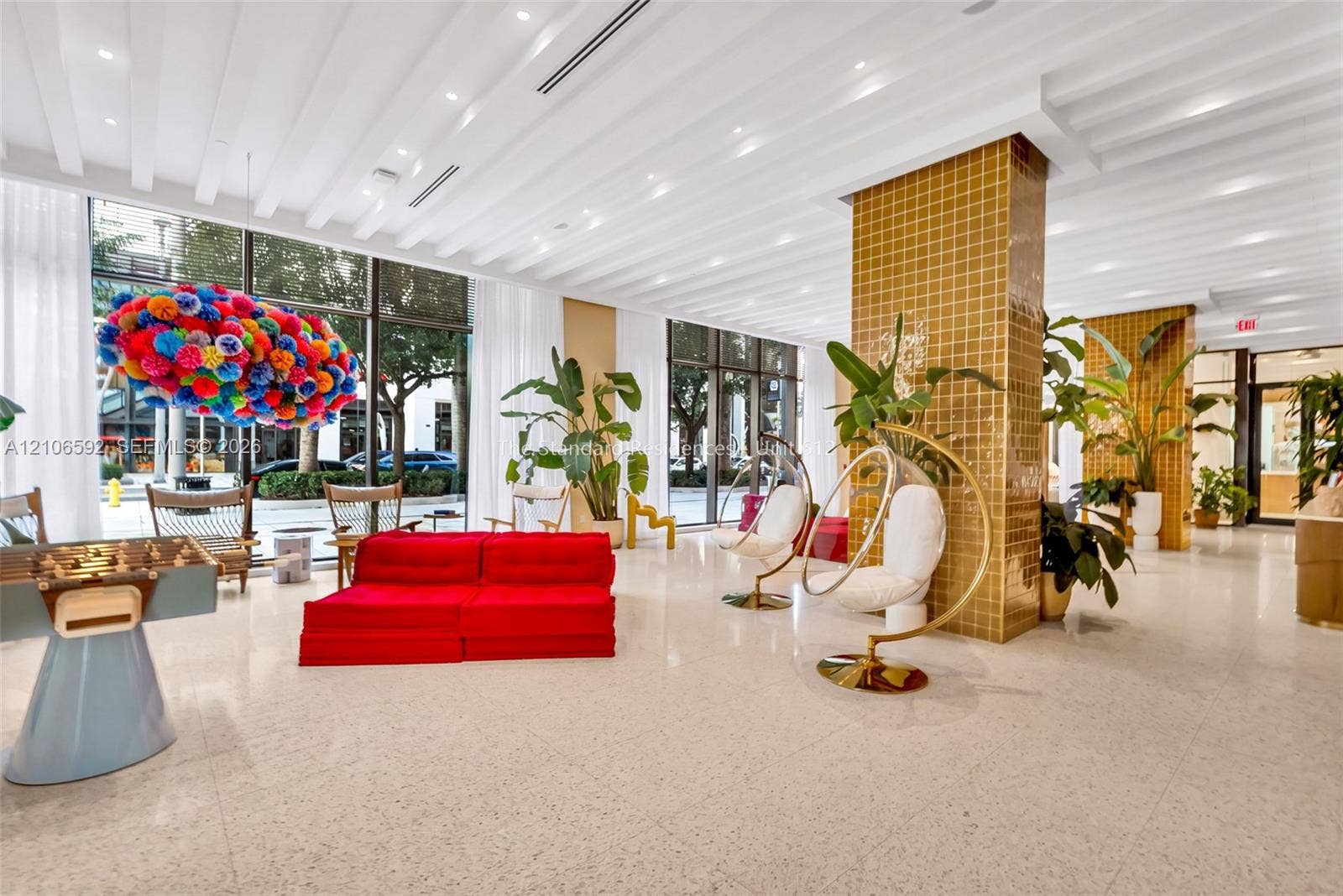 90 NE 32, #612, Miami, Miami, FL 33127 Expansive open-concept lobby featuring floor-to-ceiling windows, polished light-toned flooring, ribbed ceiling detailing with recessed lighting, and structural columns finished in gold-toned square tile