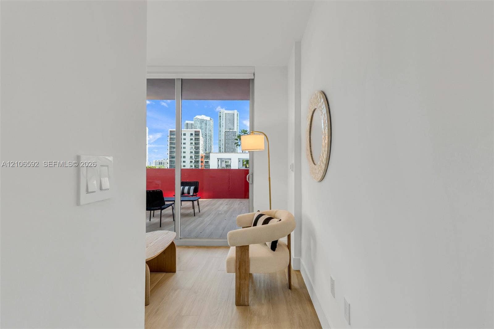 90 NE 32, #612, Miami, Miami, FL 33127 Sliding glass door leading to a balcony with wood-finish flooring and a red metal railing, featuring wood-finish flooring throughout the interior