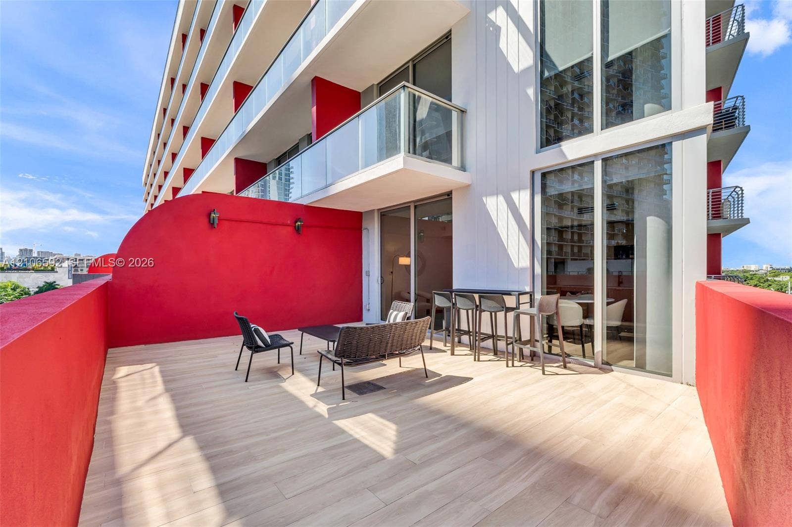 90 NE 32, #612, Miami, Miami, FL 33127 Expansive private terrace featuring wood-finish flooring, full-height glass sliding doors, and contrasting solid masonry walls