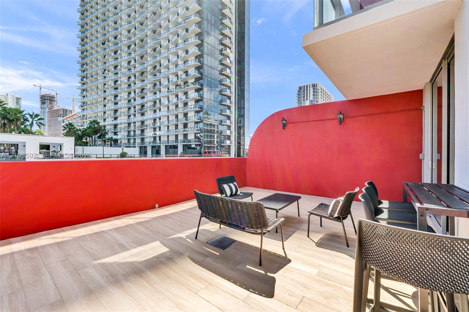 90 NE 32, #612, Miami, Miami, FL 33127 Expansive terrace featuring light wood-finish flooring, a curved red privacy wall, and wall-mounted exterior lighting