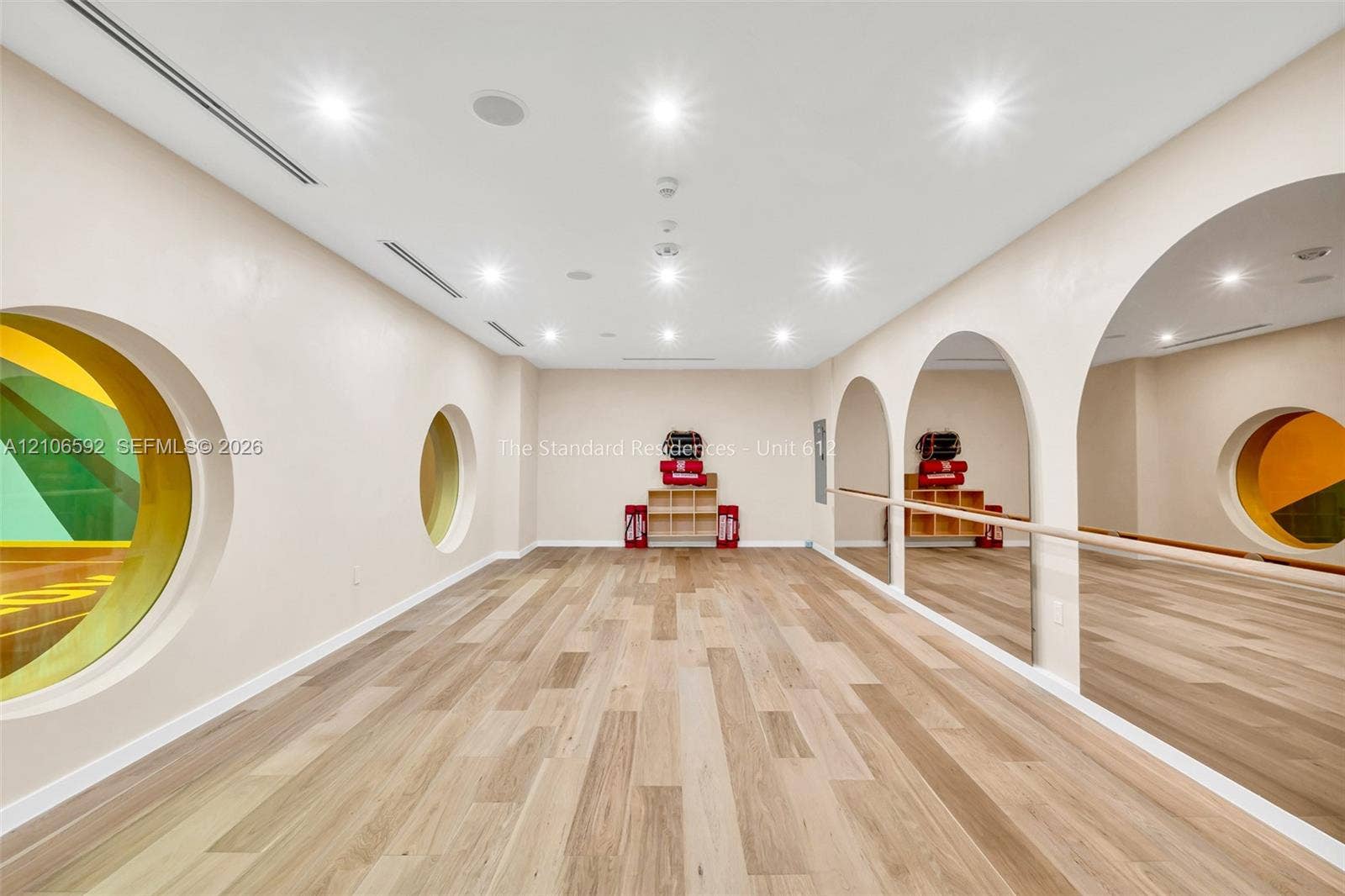 90 NE 32, #612, Miami, Miami, FL 33127 Interior space featuring wood-finish flooring, recessed lighting, arched wall mirrors, a mounted ballet barre, and circular window accents