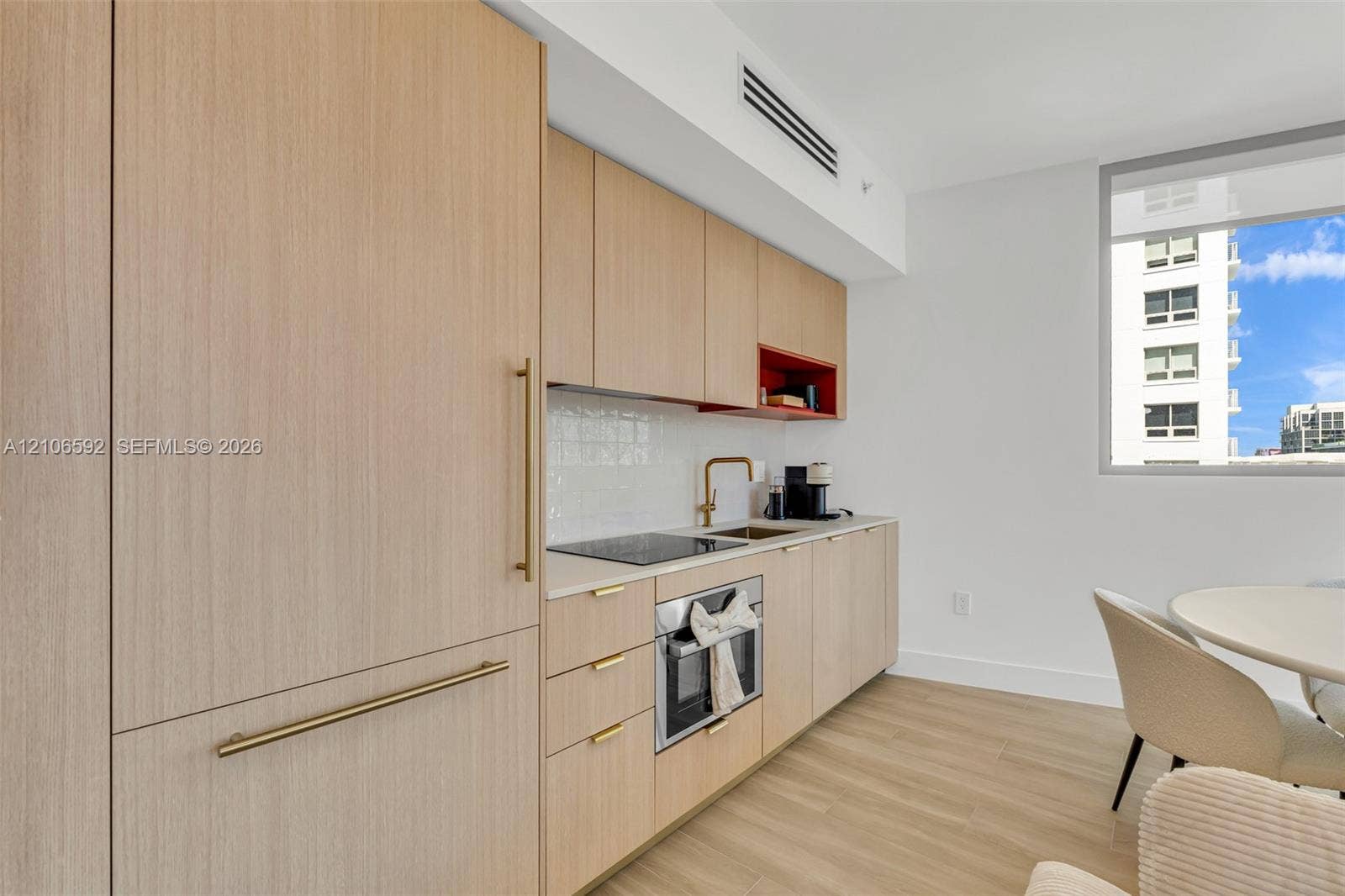 90 NE 32, #612, Miami, Miami, FL 33127 Kitchen featuring light wood-finish cabinetry, integrated appliances, light-toned countertops, tile backsplash, and metallic finish hardware