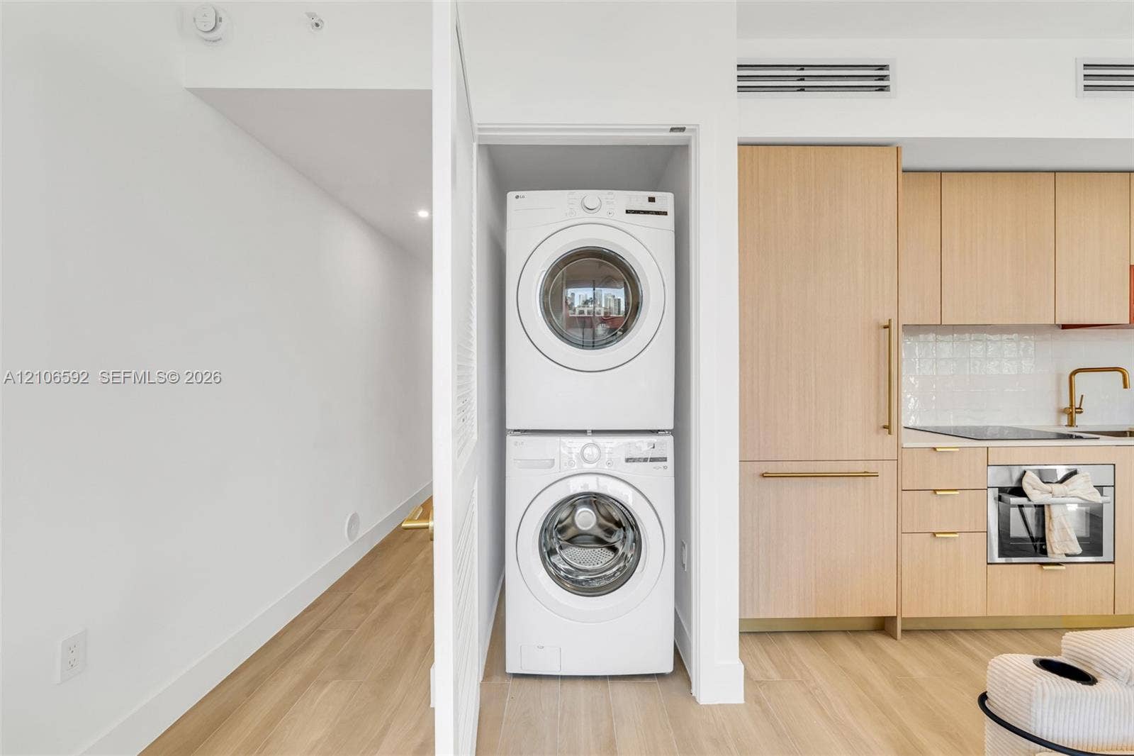 90 NE 32, #612, Miami, Miami, FL 33127 Stacked laundry center, flat-panel light wood cabinetry, integrated refrigerator, and light wood-finish flooring