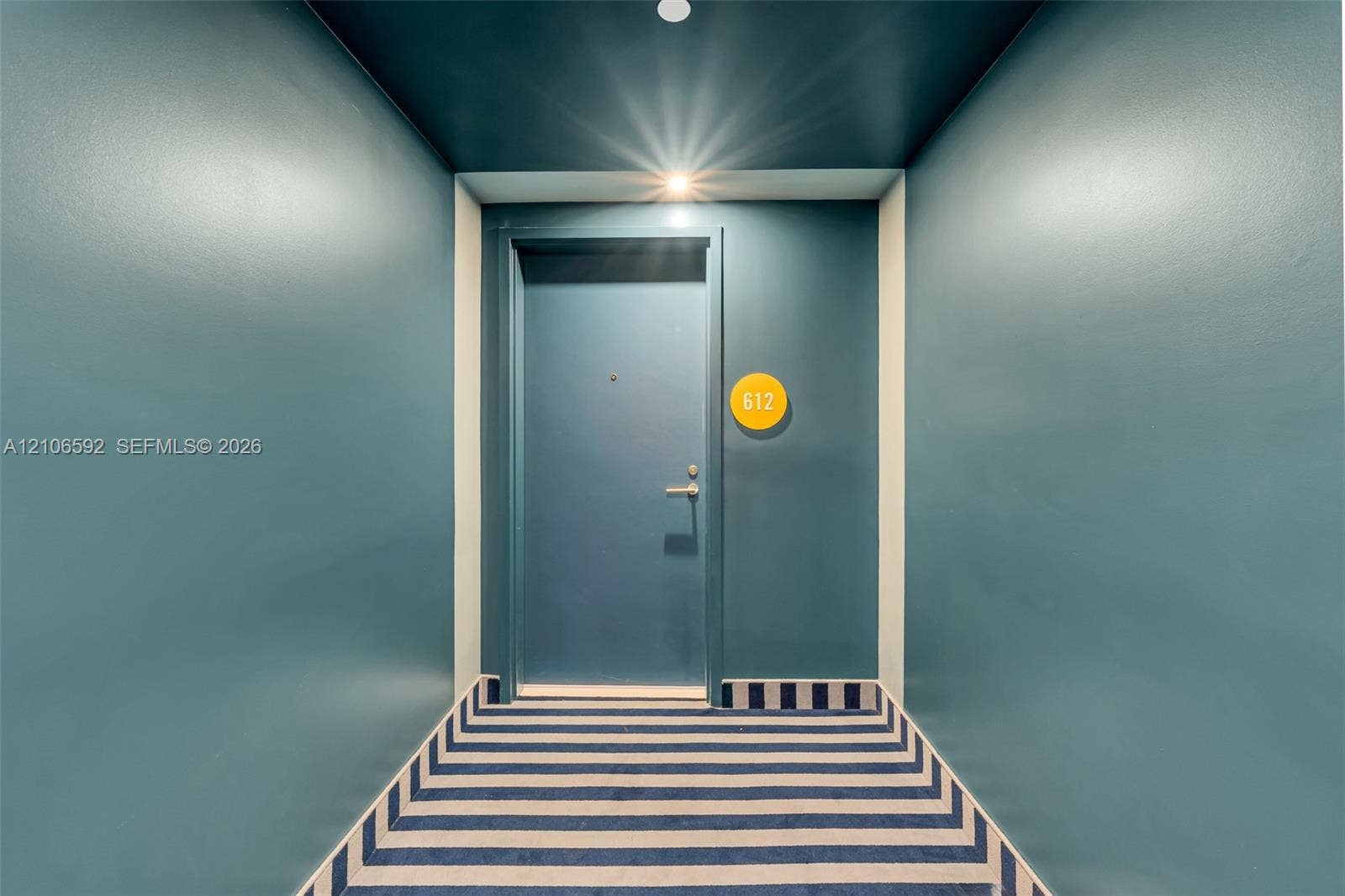 90 NE 32, #612, Miami, Miami, FL 33127 Entryway featuring saturated wall paint, a recessed ceiling light, a solid door with metallic hardware, and a striped carpet runner