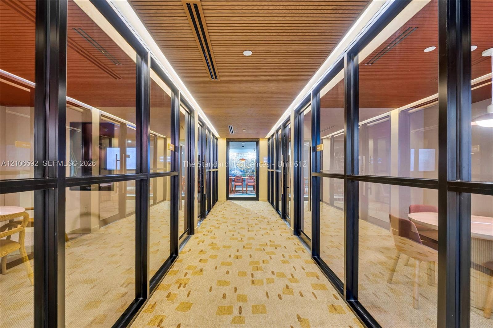 90 NE 32, #612, Miami, Miami, FL 33127 Hallway featuring floor-to-ceiling glass partitions with black frames, linear wood-slat ceiling, recessed lighting, and patterned wall-to-wall carpeting
