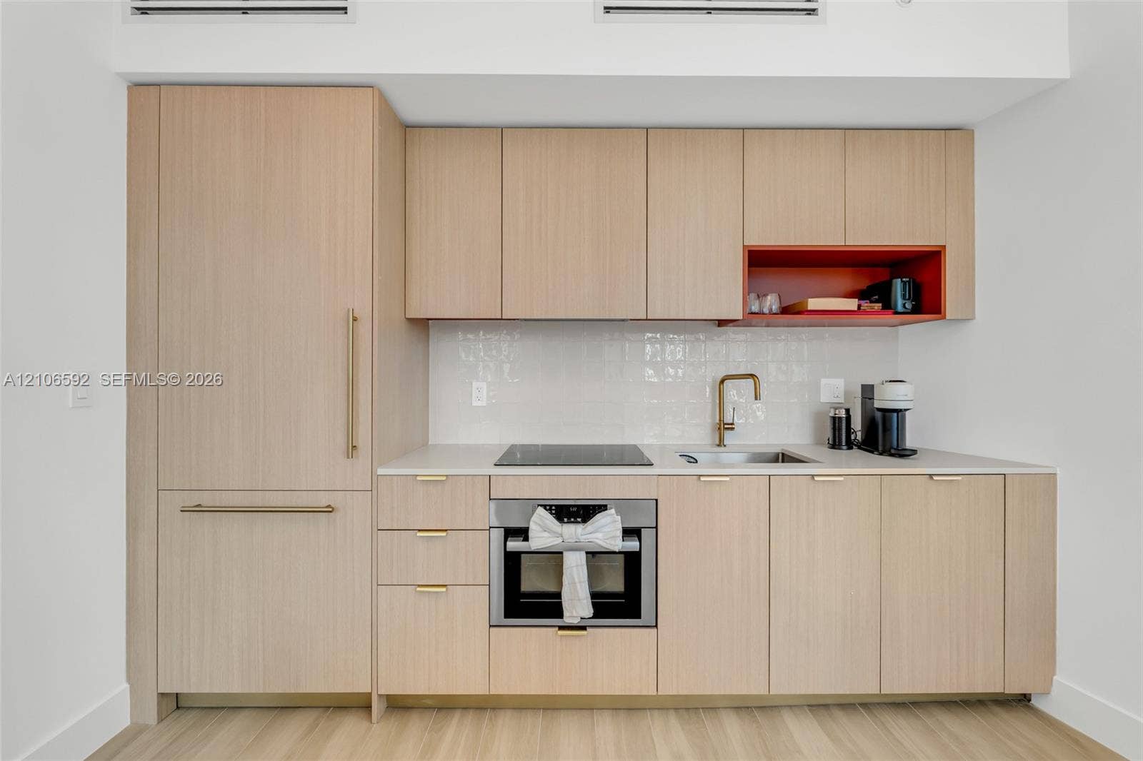 90 NE 32, #612, Miami, Miami, FL 33127 Kitchen featuring light wood-finish cabinetry, a white tile backsplash, a stone-finish countertop, integrated refrigerator, and a recessed display niche
