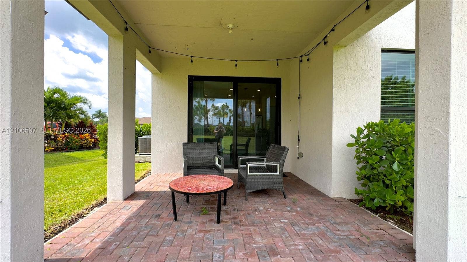 Covered patio featuring brick pavers, support columns, and sliding glass door access