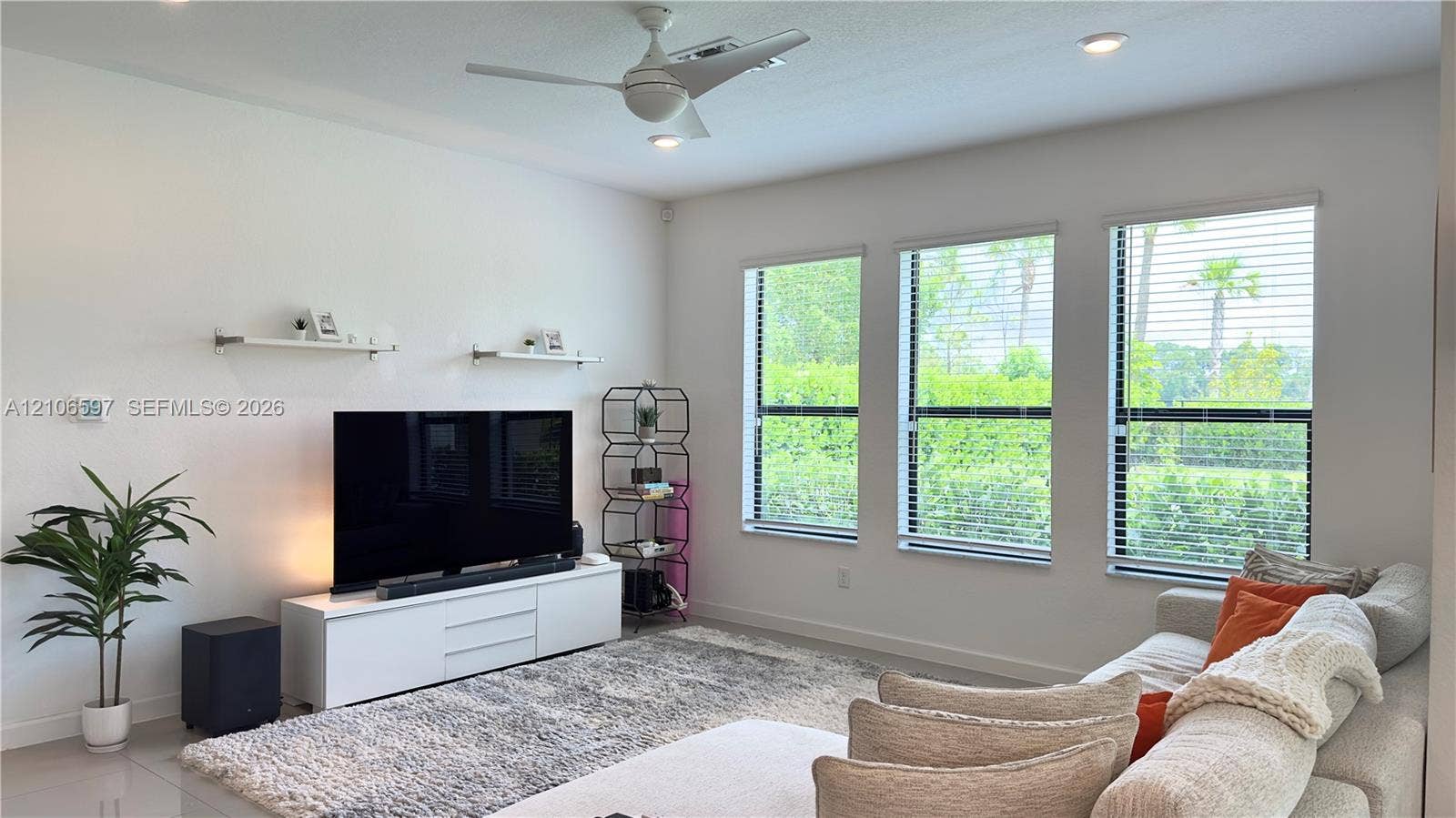 Interior space featuring a three-panel window configuration, recessed ceiling lighting, a dual-blade ceiling fan, and two wall-mounted display shelves