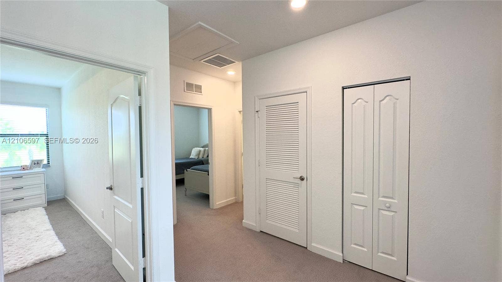 Neutral-toned carpeting, white arched-panel interior doors, and white louvered closet doors
