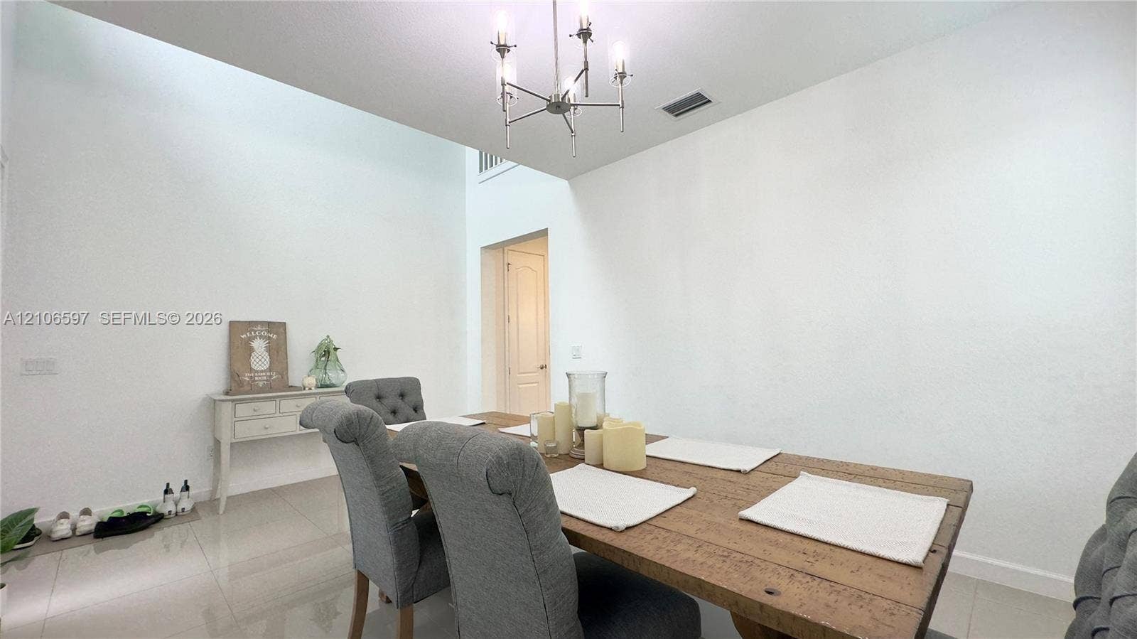 Vaulted ceilings featuring a multi-arm metallic chandelier, neutral wall finish, and polished stone-finish flooring
