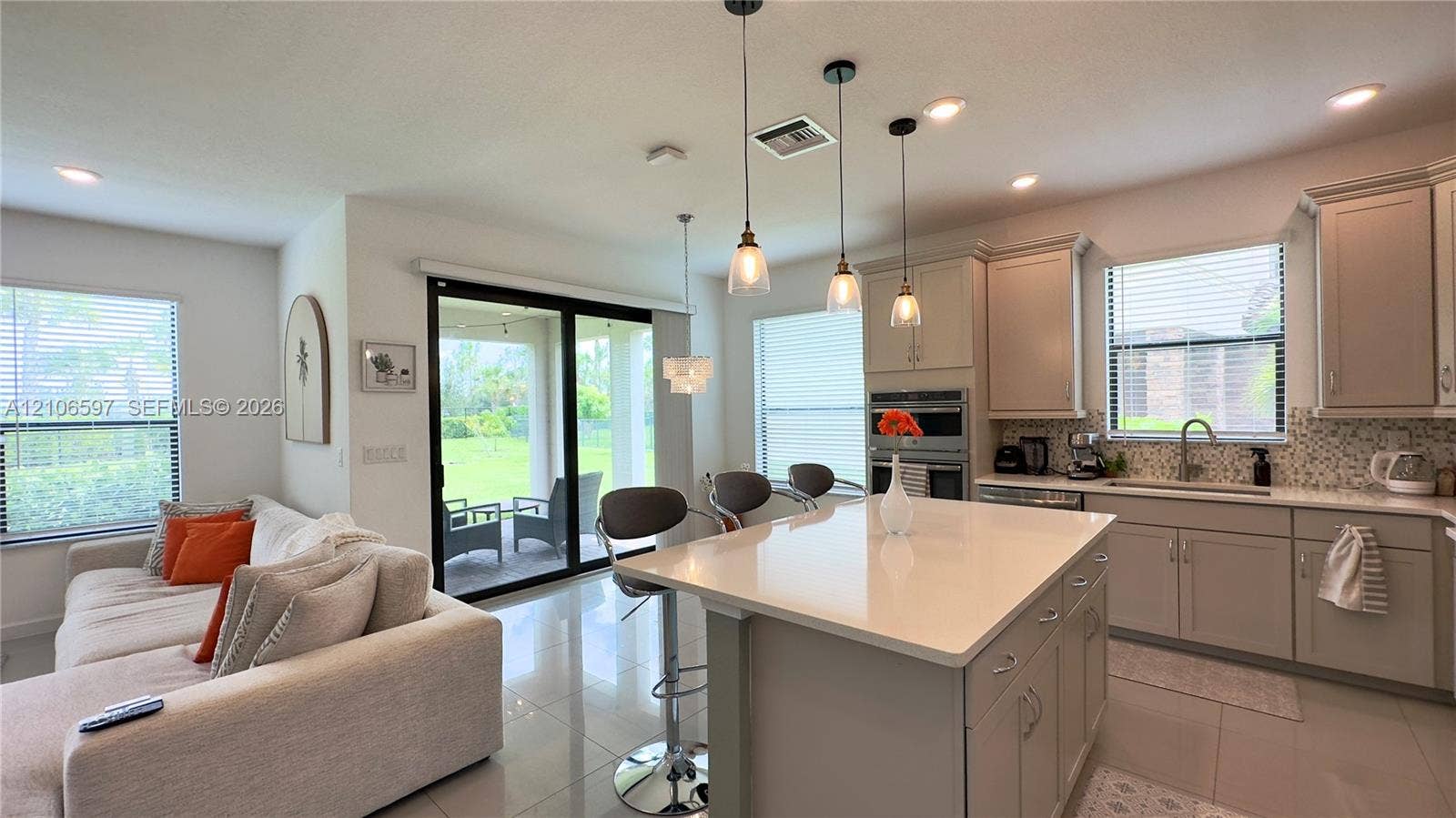 Kitchen featuring an expansive central island with stone-surface countertop, shaker-style cabinetry, built-in stainless steel oven and microwave, and polished tile flooring