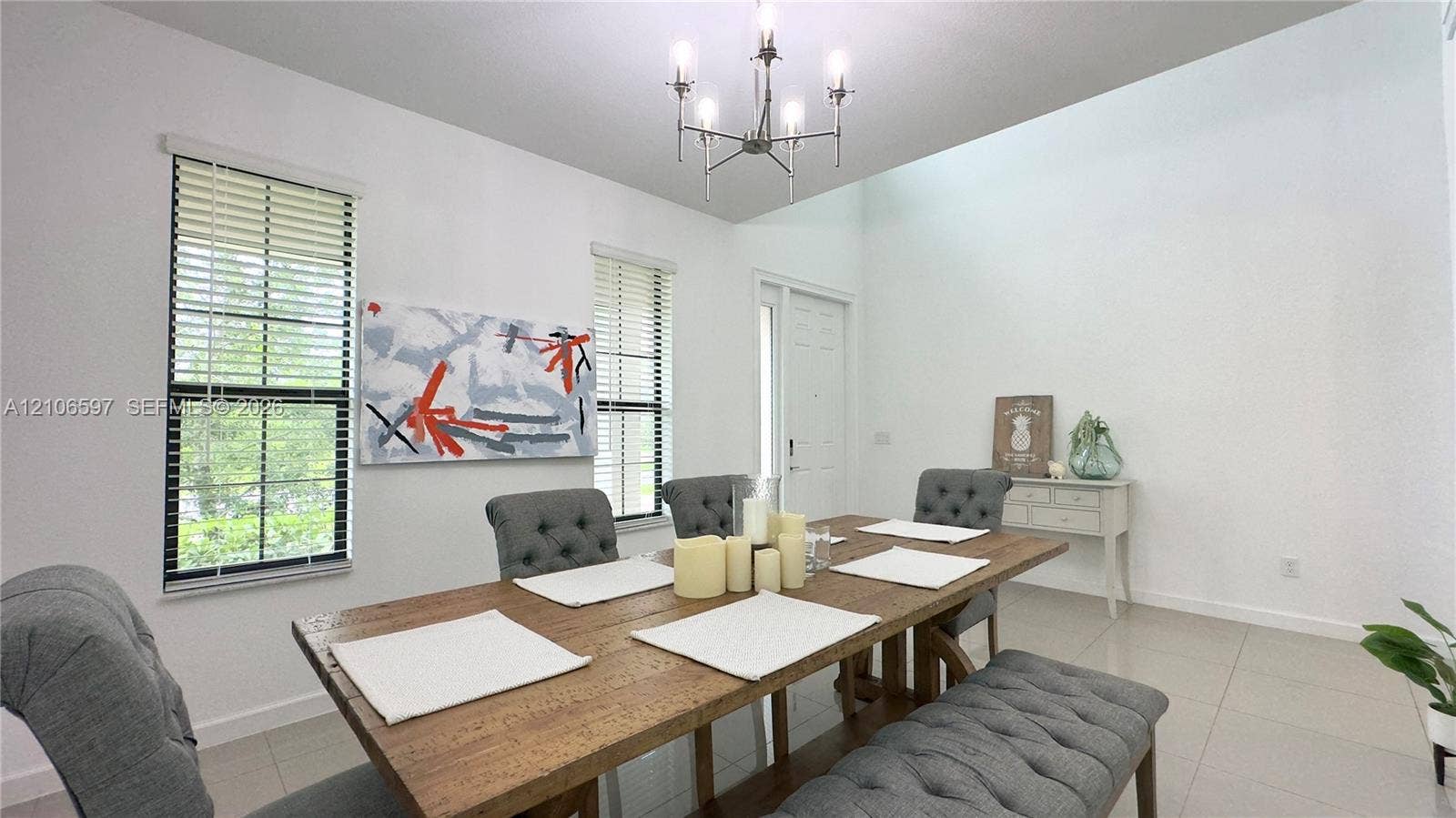 High-ceiling room featuring large windows, neutral tile flooring, and a multi-arm chandelier