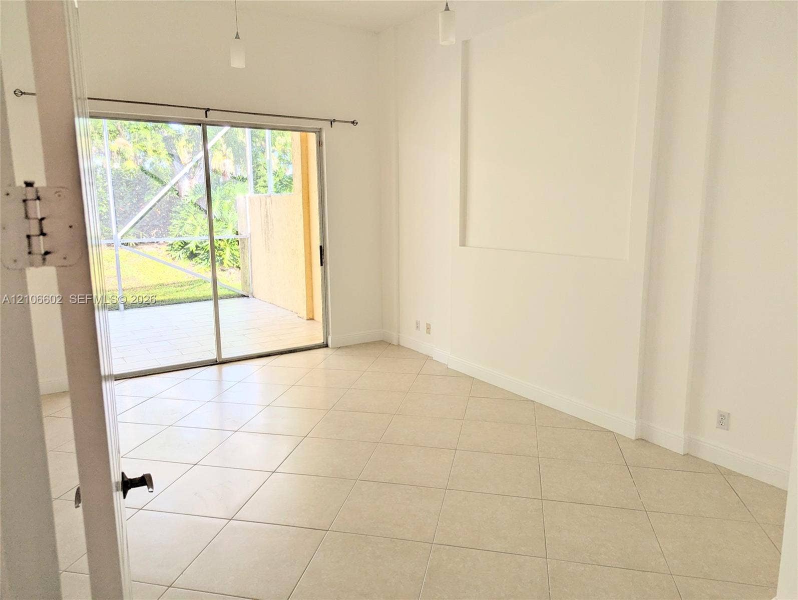 15274 Fiorenza Circle, Delray Beach, FL 33446 Interior space featuring large-format ceramic tile flooring, a recessed wall niche, sliding glass doors, and pendant lighting