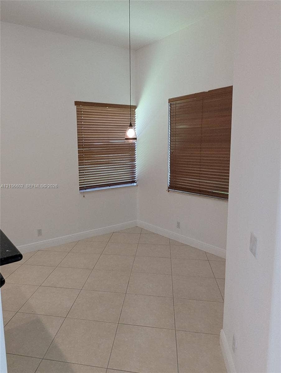 15274 Fiorenza Circle, Delray Beach, FL 33446 Neutral-toned tile flooring, two windows with horizontal blinds, and a single drop pendant light fixture