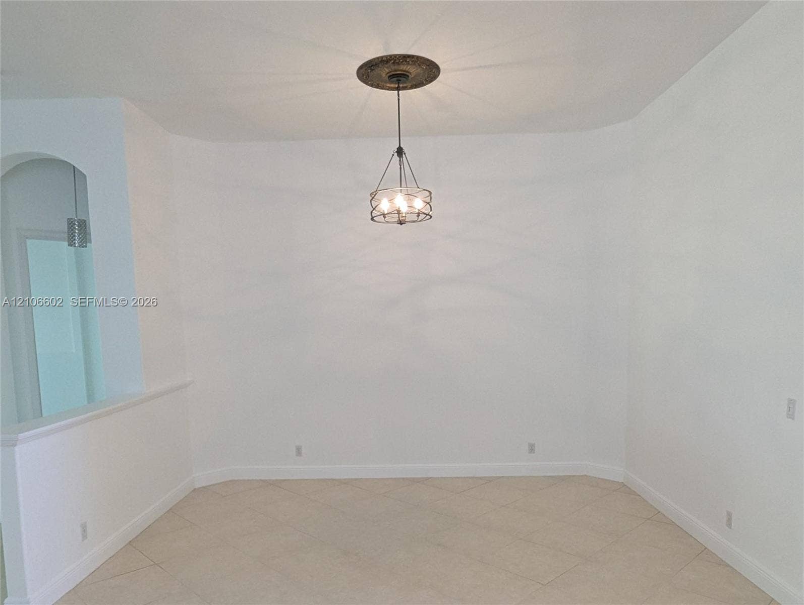 15274 Fiorenza Circle, Delray Beach, FL 33446 Neutral-toned tile flooring, decorative ceiling medallion, multi-bulb pendant fixture with metal cage frame, and an arched entryway