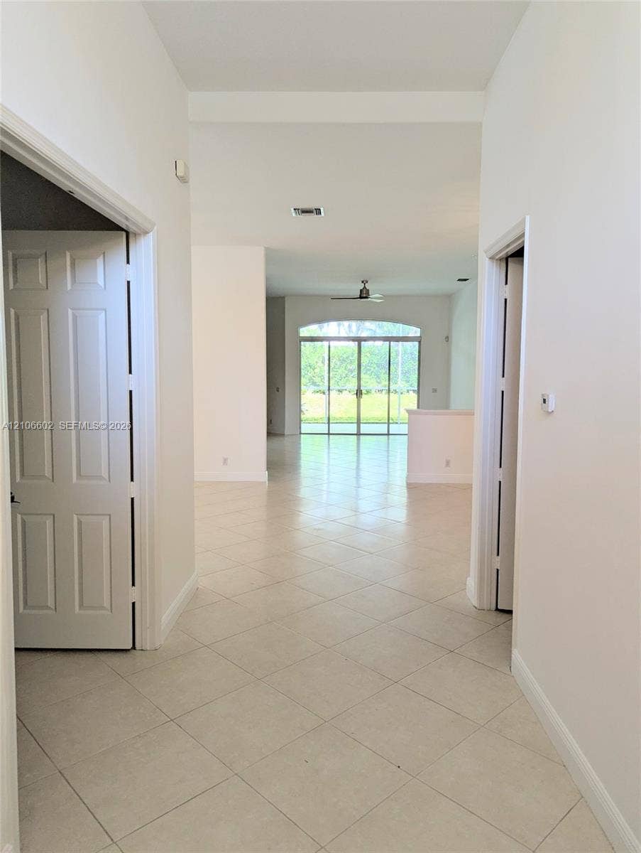 15274 Fiorenza Circle, Delray Beach, FL 33446 Interior hallway with tile flooring, arched window, and sliding glass doors