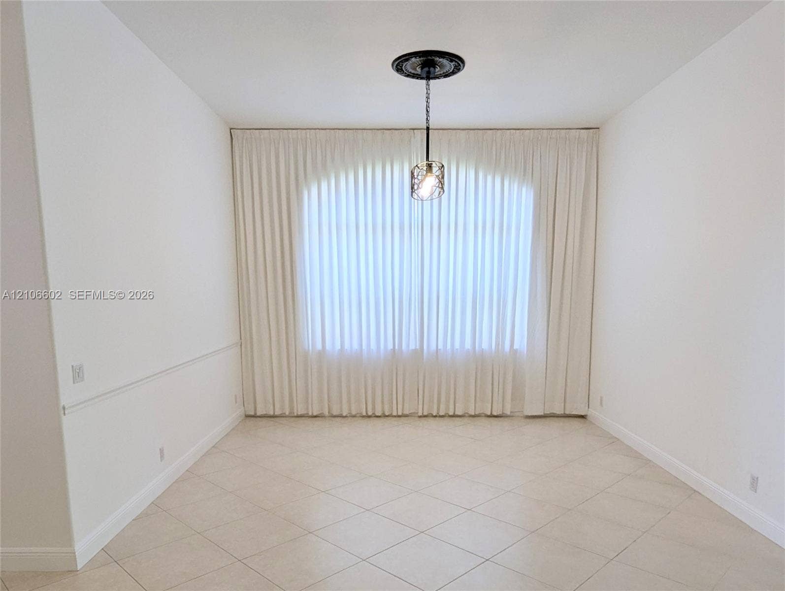 15274 Fiorenza Circle, Delray Beach, FL 33446 Arched window featuring full-length drapery, tile flooring, crown molding, and a ceiling-mounted pendant light with an ornate decorative medallion