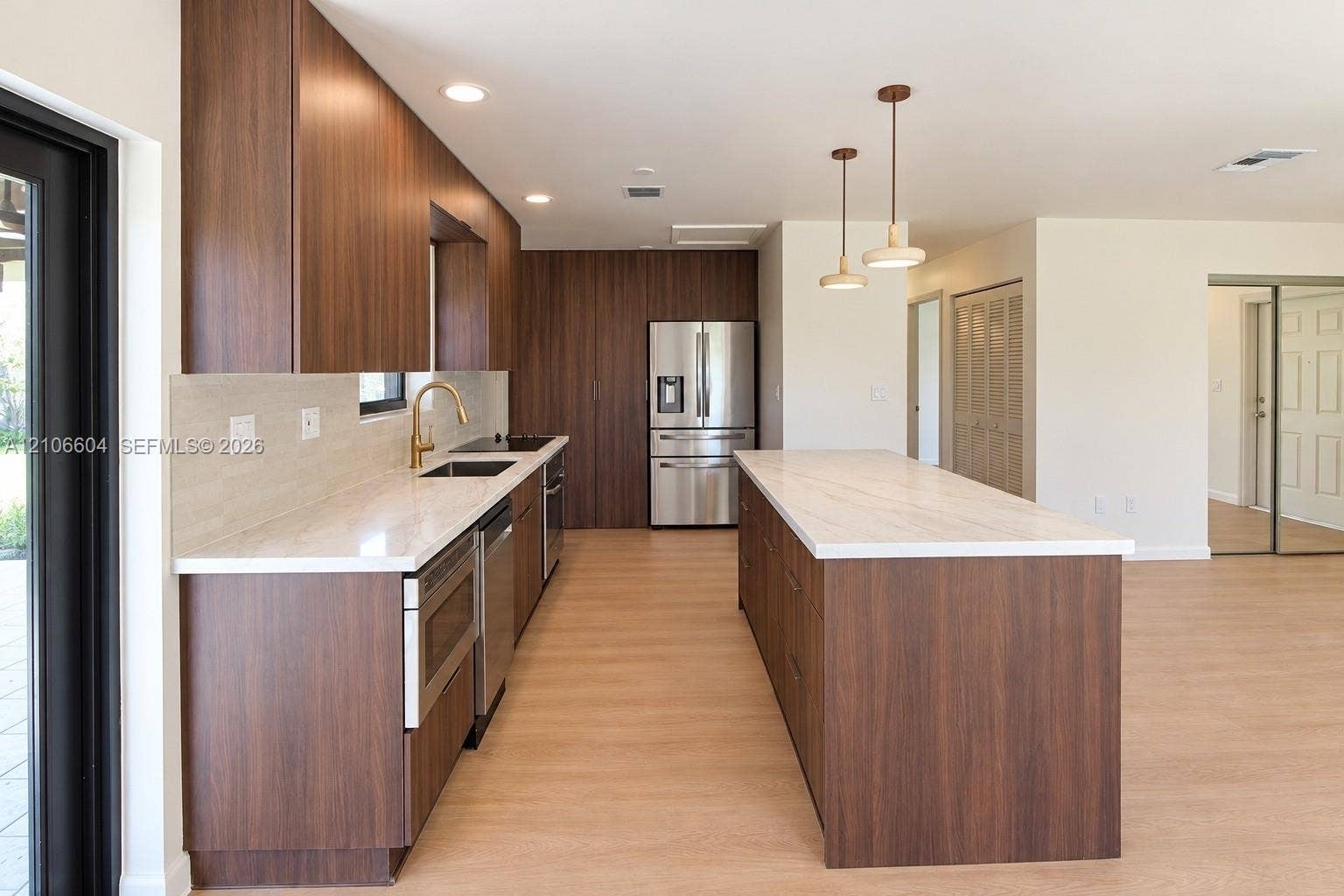 Kitchen featuring wood-finish cabinetry, stone-surface countertops, stainless steel appliances, a center island, and pendant lighting