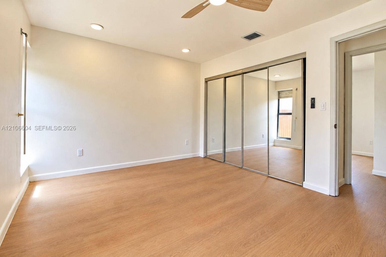 Room featuring wood-finish flooring, recessed lighting, a ceiling fan with light fixture, and floor-to-ceiling mirrored sliding closet doors