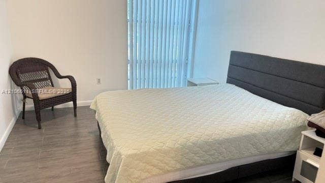 17570 Atlantic Boulevard, #105, Sunny Isles Beach, Sunny Isles Beach, FL 33160 Multi-story residential building featuring a white facade, uniform multi-pane windows, black metal perimeter fencing, manicured landscaping with mature palms, and a dedicated parking area