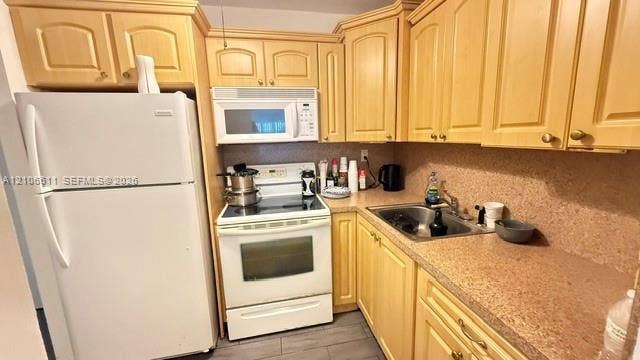 17570 Atlantic Boulevard, #105, Sunny Isles Beach, Sunny Isles Beach, FL 33160 Kitchen featuring light-tone wood cabinetry, solid-surface countertops, a stainless steel undermount sink, and white appliances including a range and microwave