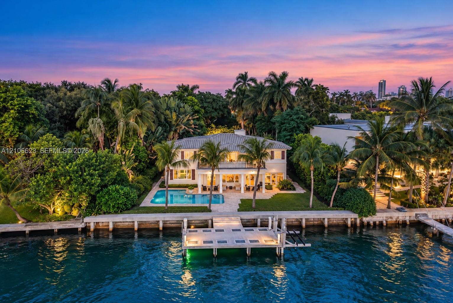 2312 Bay Avenue, Miami Beach, FL 33140 Waterfront estate featuring a private dock, swimming pool, two-story covered loggia, and landscaped grounds with mature palm trees