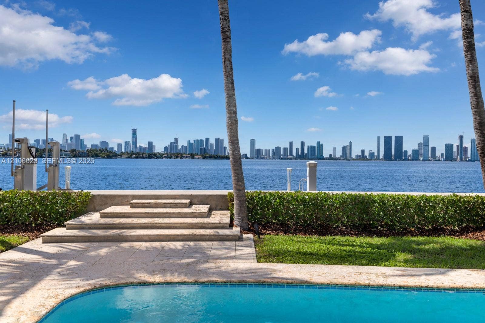 2312 Bay Avenue, Miami Beach, FL 33140 Waterfront property featuring a swimming pool, stone-paved decking, tiered stone steps, and manicured perimeter hedging