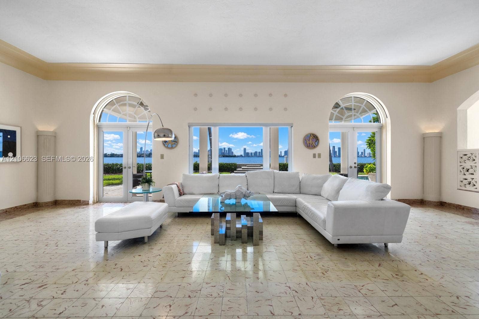 2312 Bay Avenue, Miami Beach, FL 33140 Living area featuring stone flooring, arched glass double doors, large central picture window, decorative crown molding, and recessed wall columns