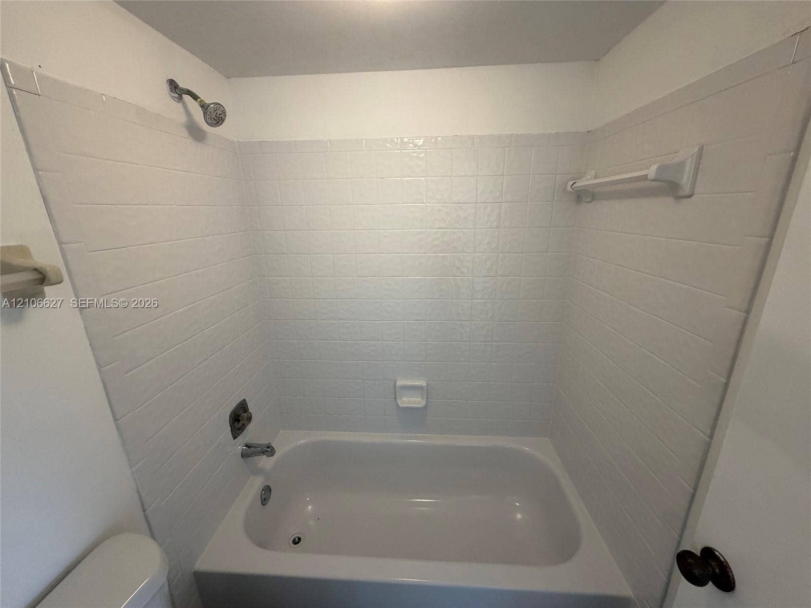 9954 Twin Lakes Drive, #7-O, Coral Springs, Coral Springs, FL 33071 Tub and shower combination featuring a white tile surround, integrated soap dish, chrome shower head, and wall-mounted towel bar