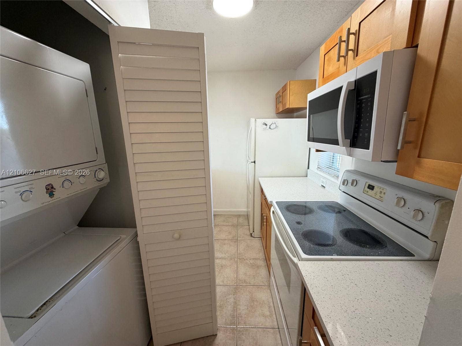9954 Twin Lakes Drive, #7-O, Coral Springs, Coral Springs, FL 33071 Kitchen featuring white stone-finish countertops, natural wood cabinetry, integrated white appliances, louvered closet doors, and tile flooring