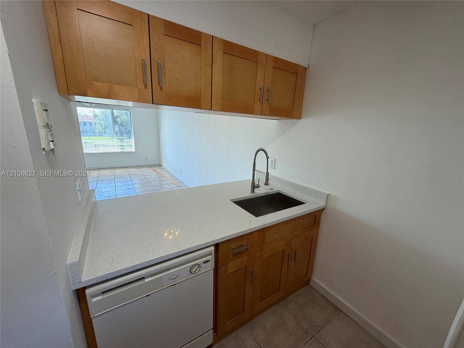 9954 Twin Lakes Drive, #7-O, Coral Springs, Coral Springs, FL 33071 Kitchen area featuring wood cabinetry, solid-surface countertop with integrated backsplash, undermount sink with gooseneck faucet, and white dishwasher