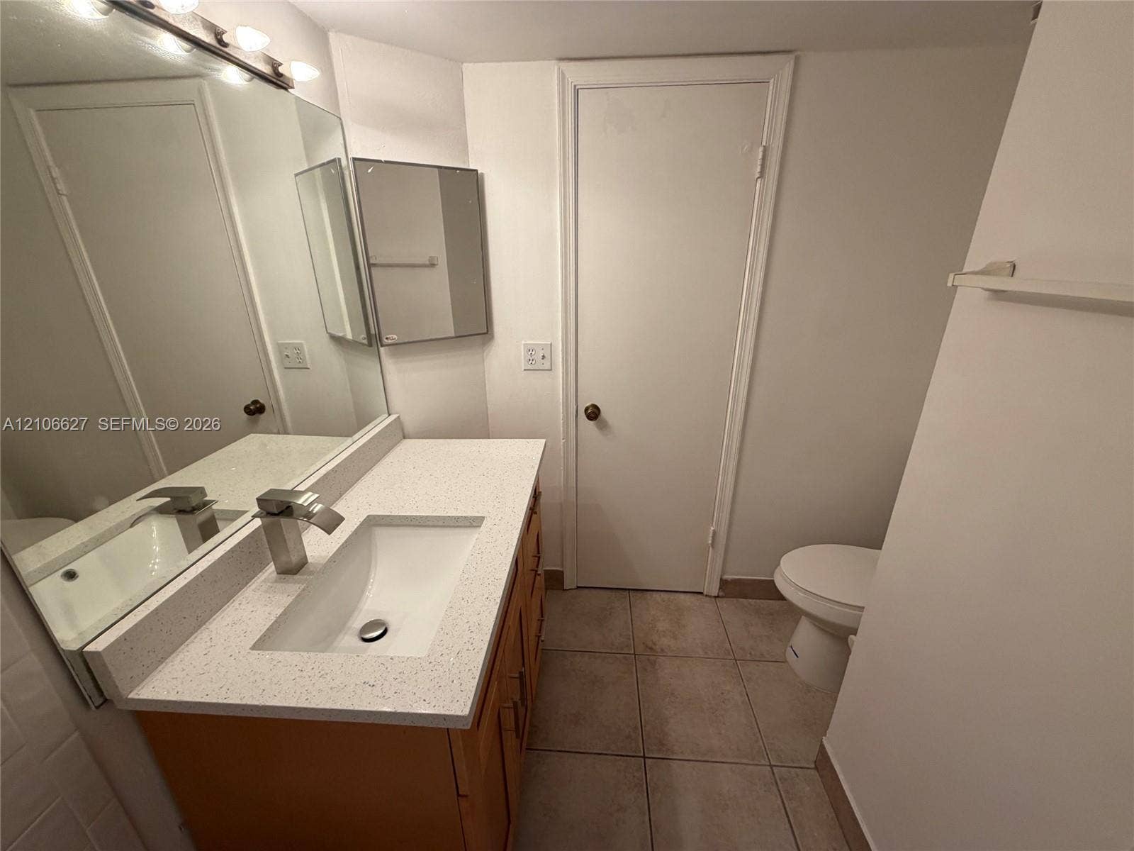 9954 Twin Lakes Drive, #7-O, Coral Springs, Coral Springs, FL 33071 Vanity featuring a stone-composite countertop with an integrated rectangular sink and modern metal faucet, complemented by a large wall-mounted mirror, ceramic tile flooring, and neutral wall cabinetry