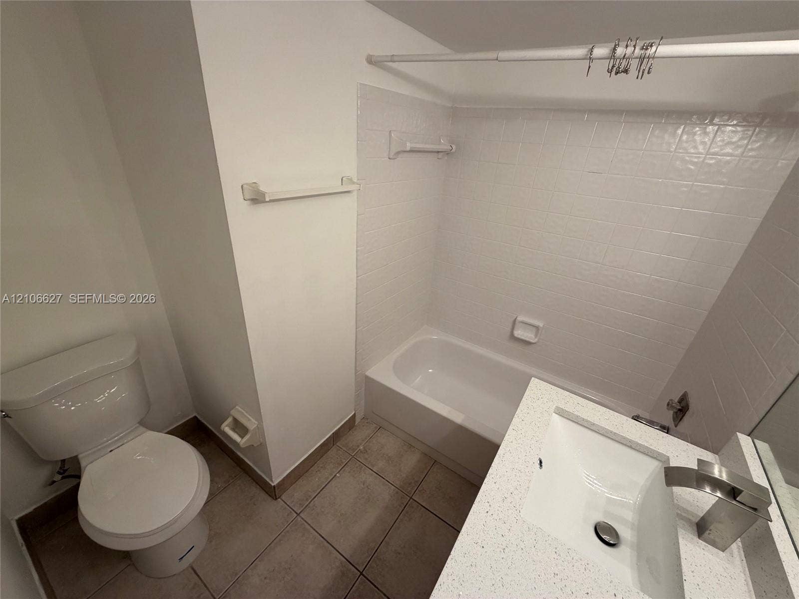 9954 Twin Lakes Drive, #7-O, Coral Springs, Coral Springs, FL 33071 Bathroom featuring a vanity with a rectangular sink, stone-composite countertop, and a brushed-metal faucet, accompanied by a tiled tub enclosure and large-format floor tile