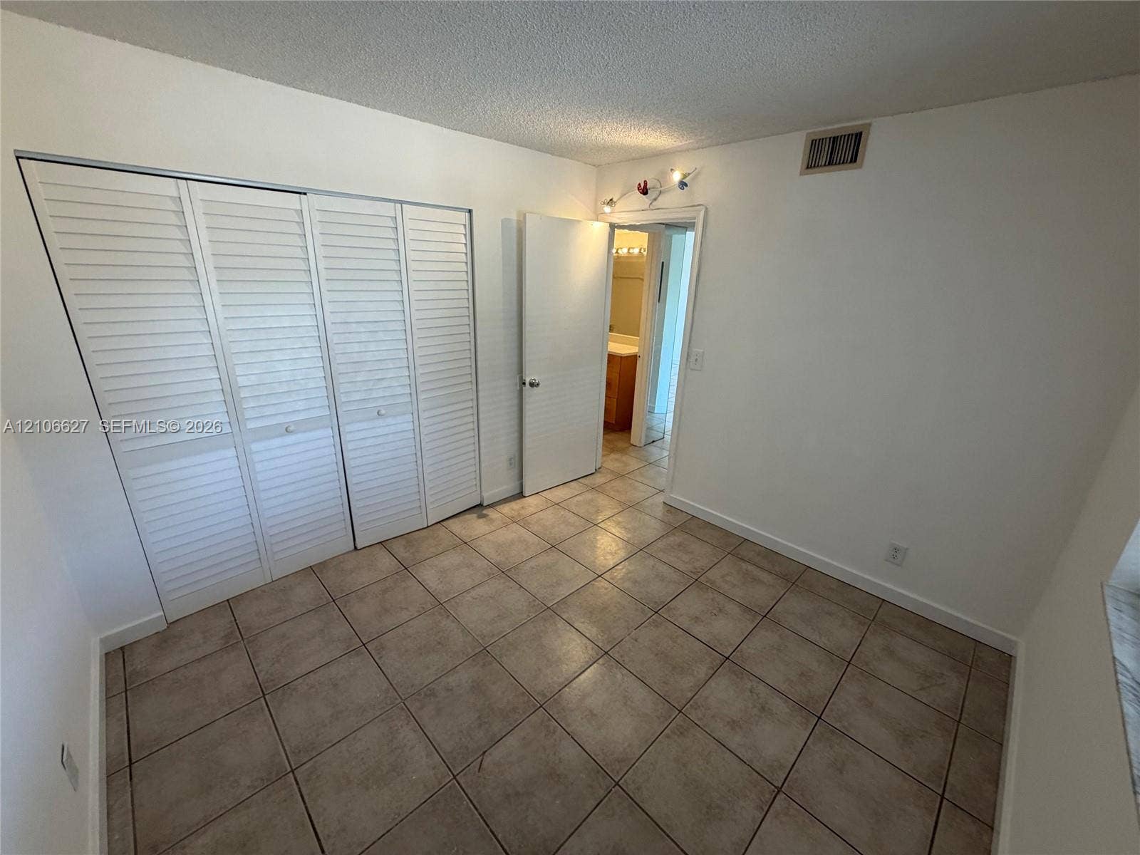 Room featuring tile flooring, white accordion-style closet doors, and multi-directional track lighting