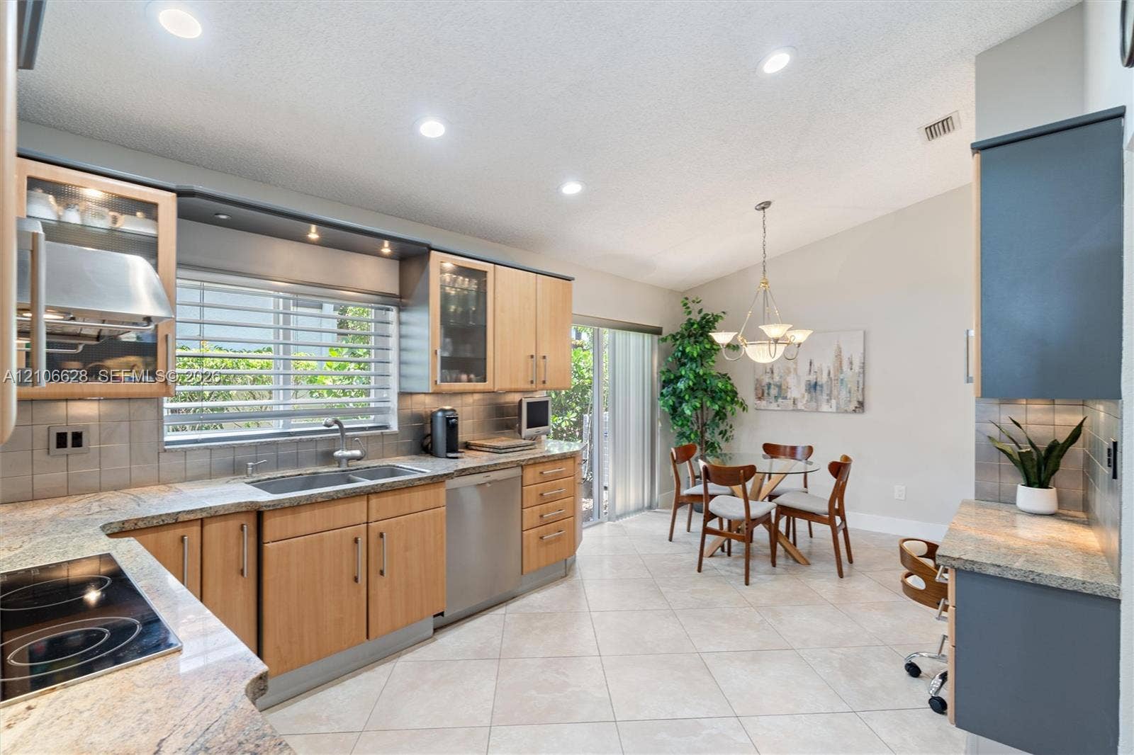 7259 Via Palomar, Boca Raton, FL 33433 Kitchen featuring light-finish wood cabinetry, integrated stainless steel appliances, neutral stone-finish countertops, tile backsplash, and ceramic tile flooring
