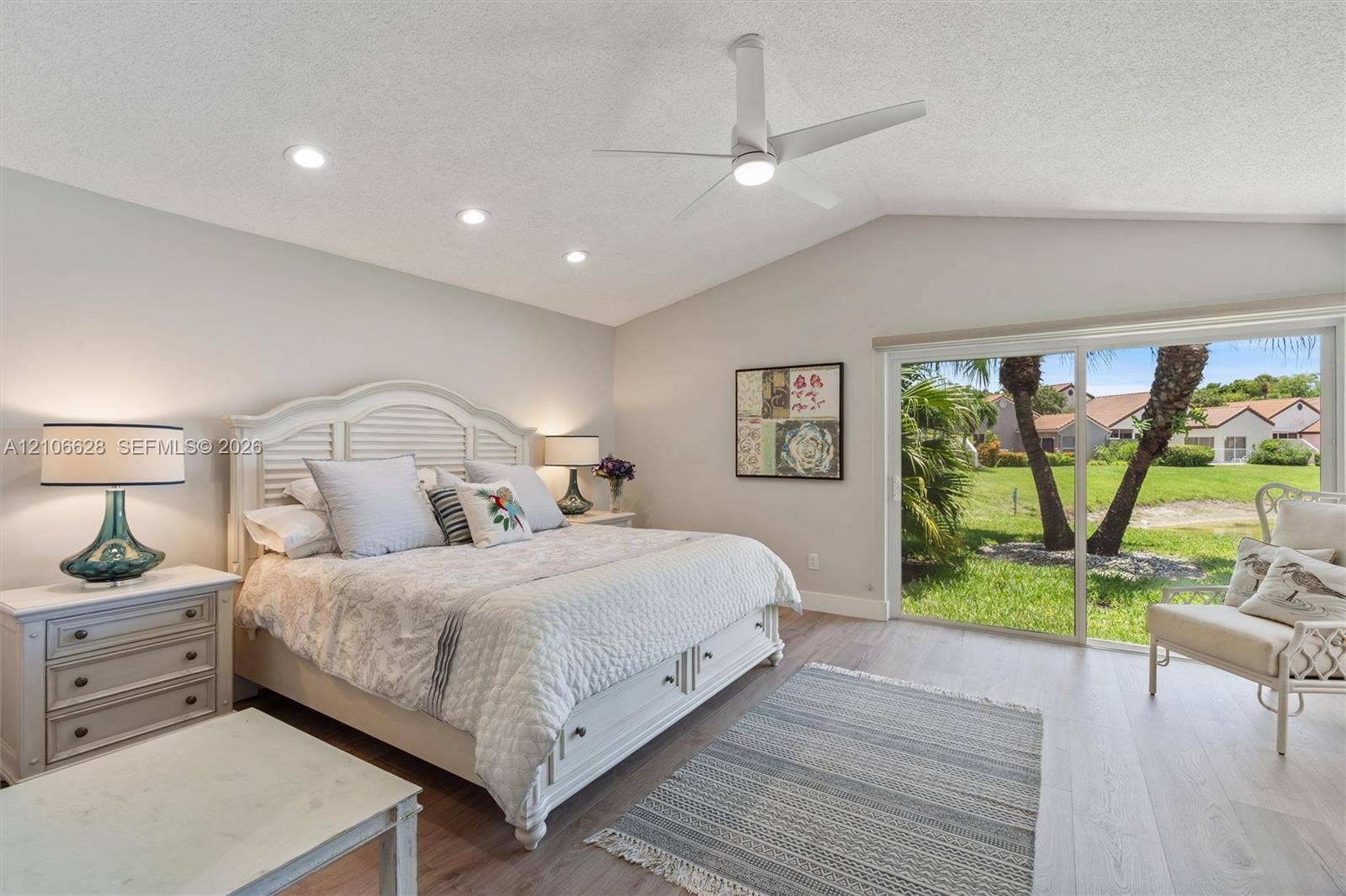 7259 Via Palomar, Boca Raton, FL 33433 Vaulted ceiling with recessed lighting and a central ceiling fan, wood-finish flooring, and sliding glass doors with exterior landscaping