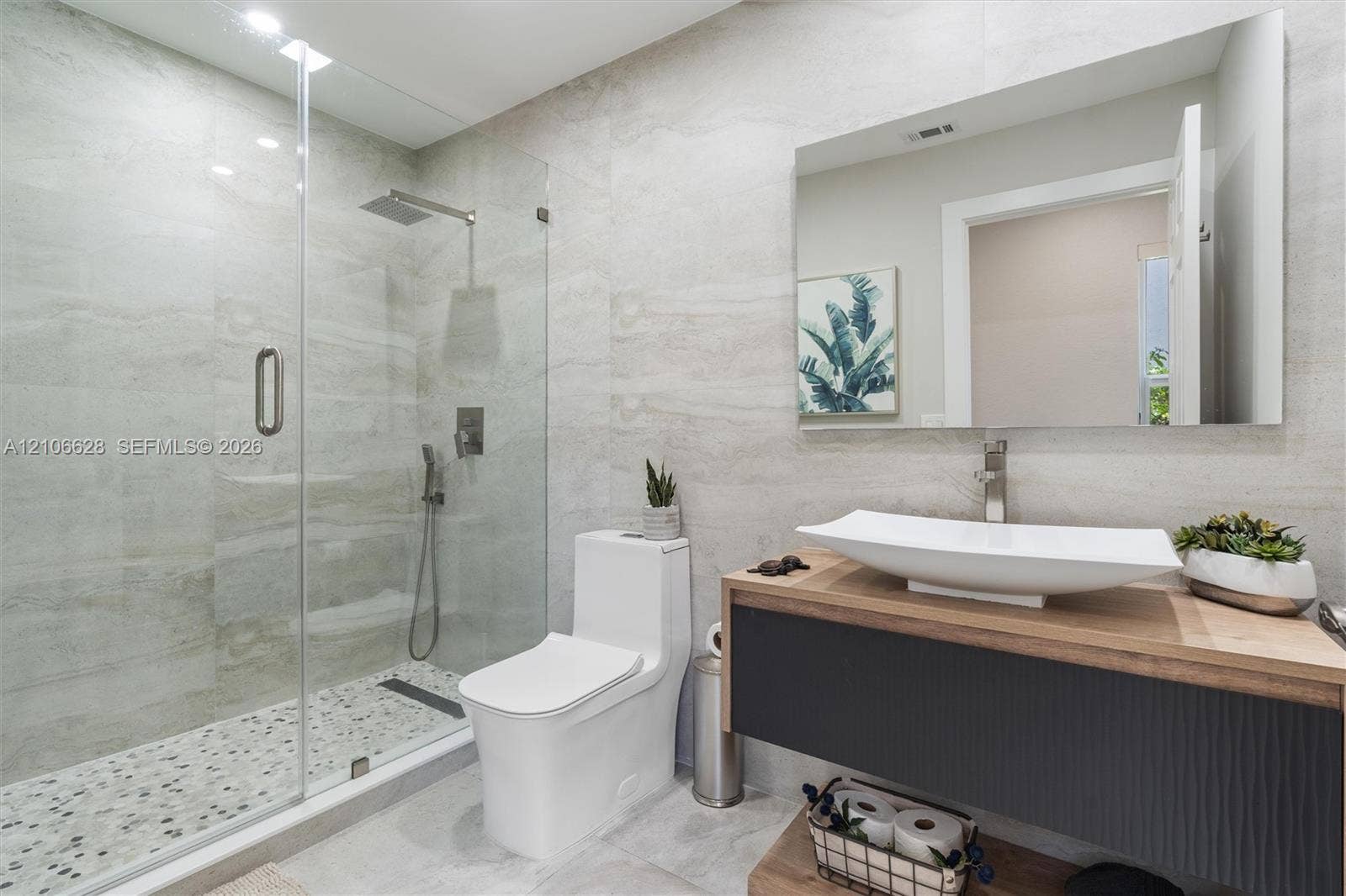 7259 Via Palomar, Boca Raton, FL 33433 Floating vanity with a vessel sink and wood-finish countertop, glass-enclosed shower with a rainfall showerhead, and wall-to-wall stone-finish tile