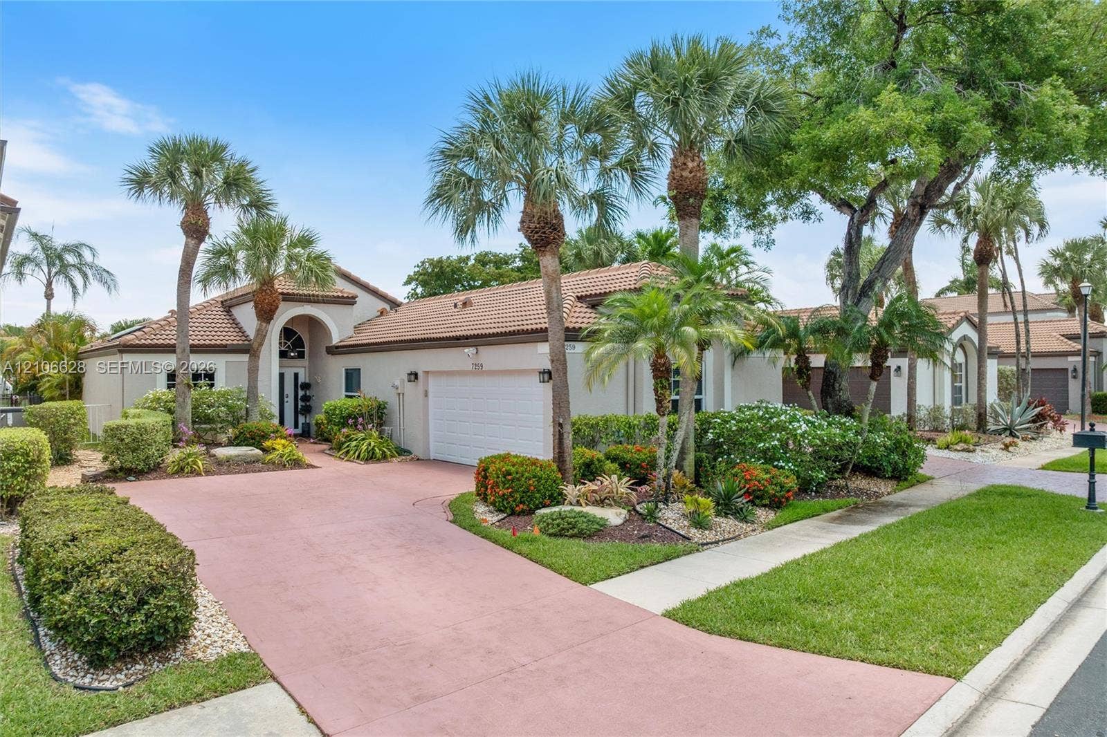 7259 Via Palomar, Boca Raton, FL 33433 Single-story exterior featuring a tile roof, multi-car garage, arched entryway, and landscaped grounds with mature palm trees