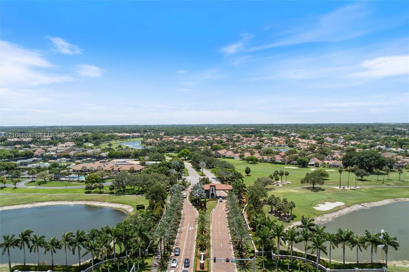 7259 Via Palomar, Boca Raton, FL 33433 Gated community entrance featuring brick-paved roadways, perimeter landscaping with mature palms, and surrounding golf course grounds with multiple water features