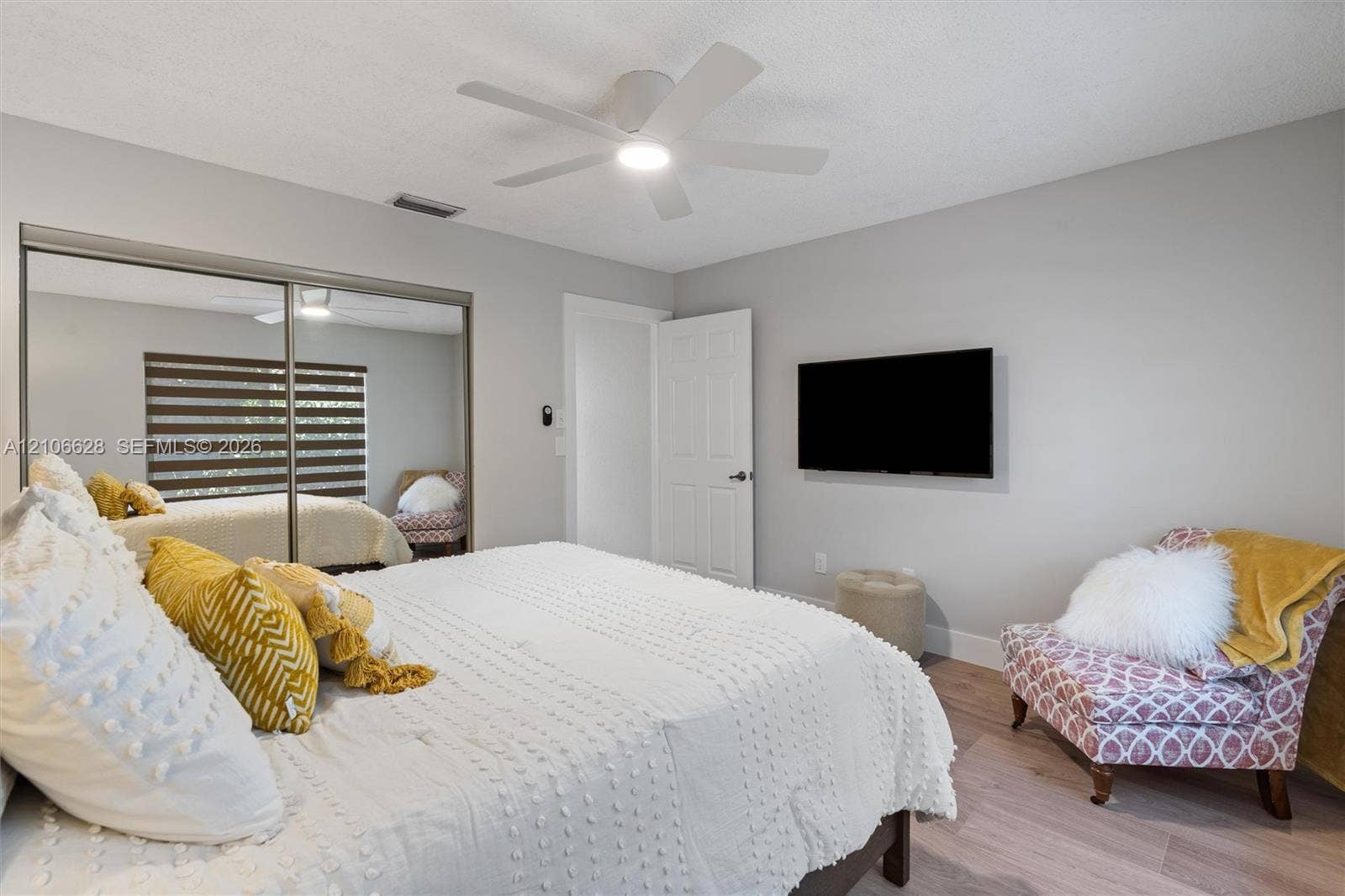 7259 Via Palomar, Boca Raton, FL 33433 Neutral interior walls, wood-finish flooring, sliding mirrored closet doors, and a ceiling-mounted light fixture with fan