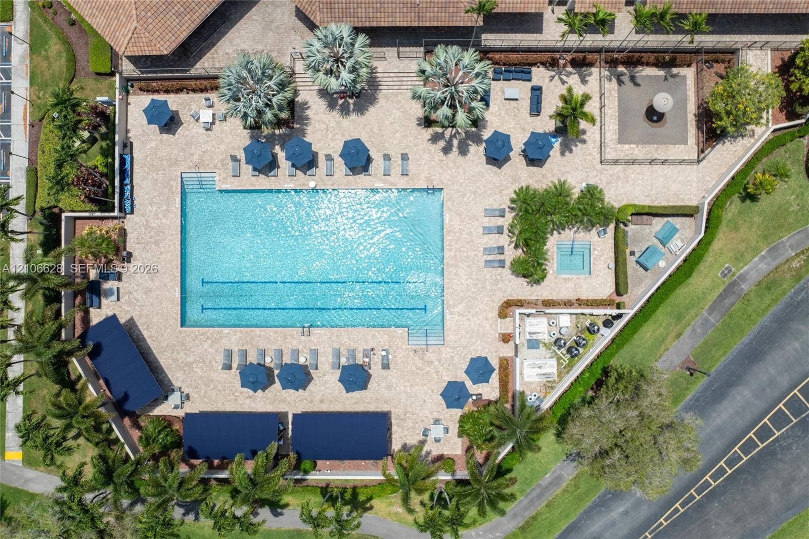 7259 Via Palomar, Boca Raton, FL 33433 Aerial view of a swimming pool complex featuring a lap lane configuration, an integrated spa, paved pool deck, and shaded structures
