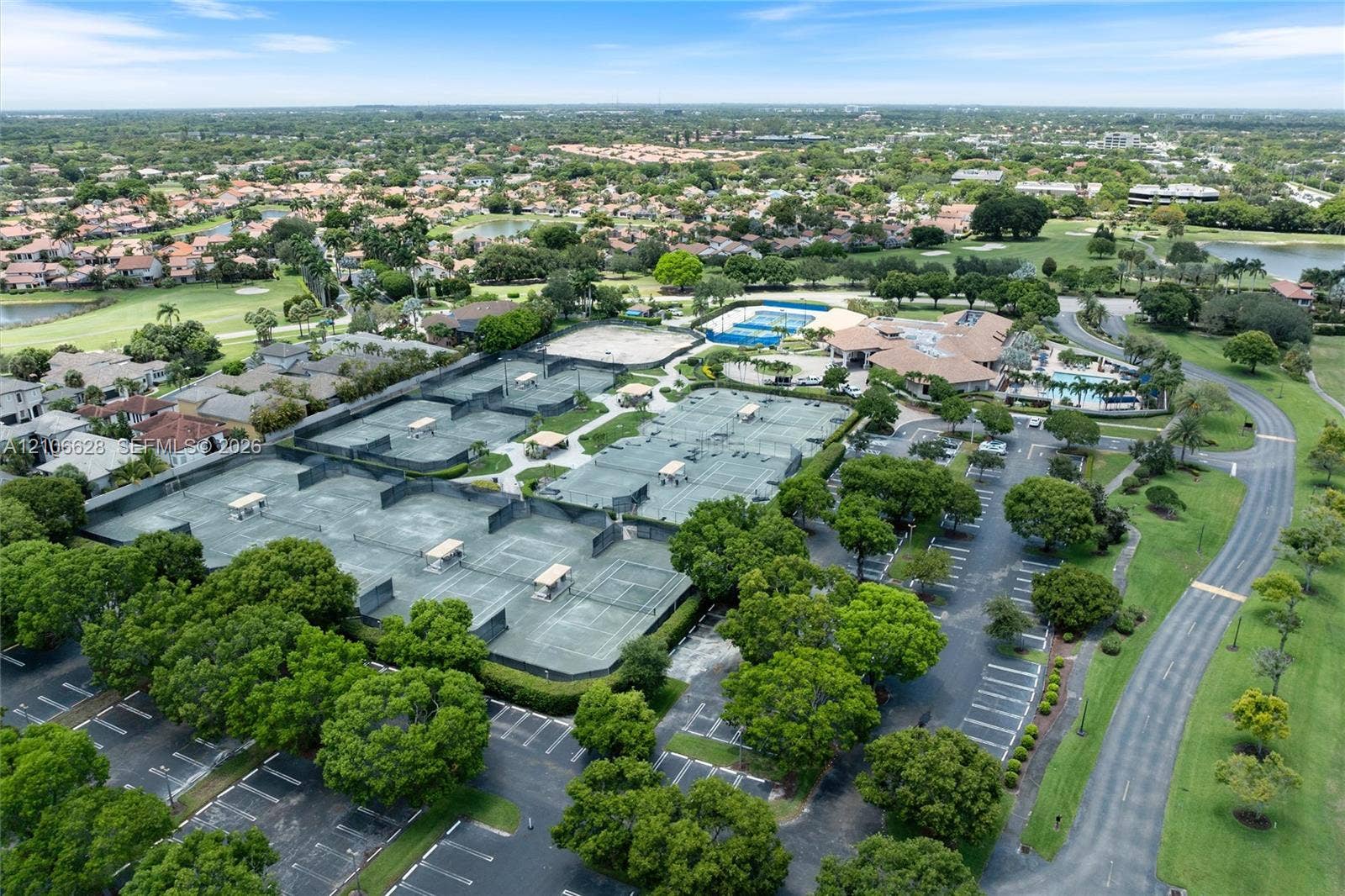 7259 Via Palomar, Boca Raton, FL 33433 Aerial perspective of a recreation complex featuring multiple tennis courts, a swimming pool, a clubhouse building, and paved parking areas
