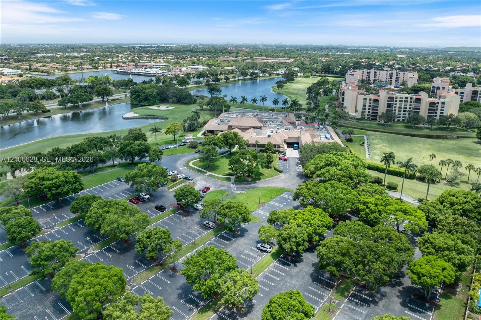 7259 Via Palomar, Boca Raton, FL 33433 Aerial perspective featuring mature landscaping, paved surface parking, multi-story buildings, and water features