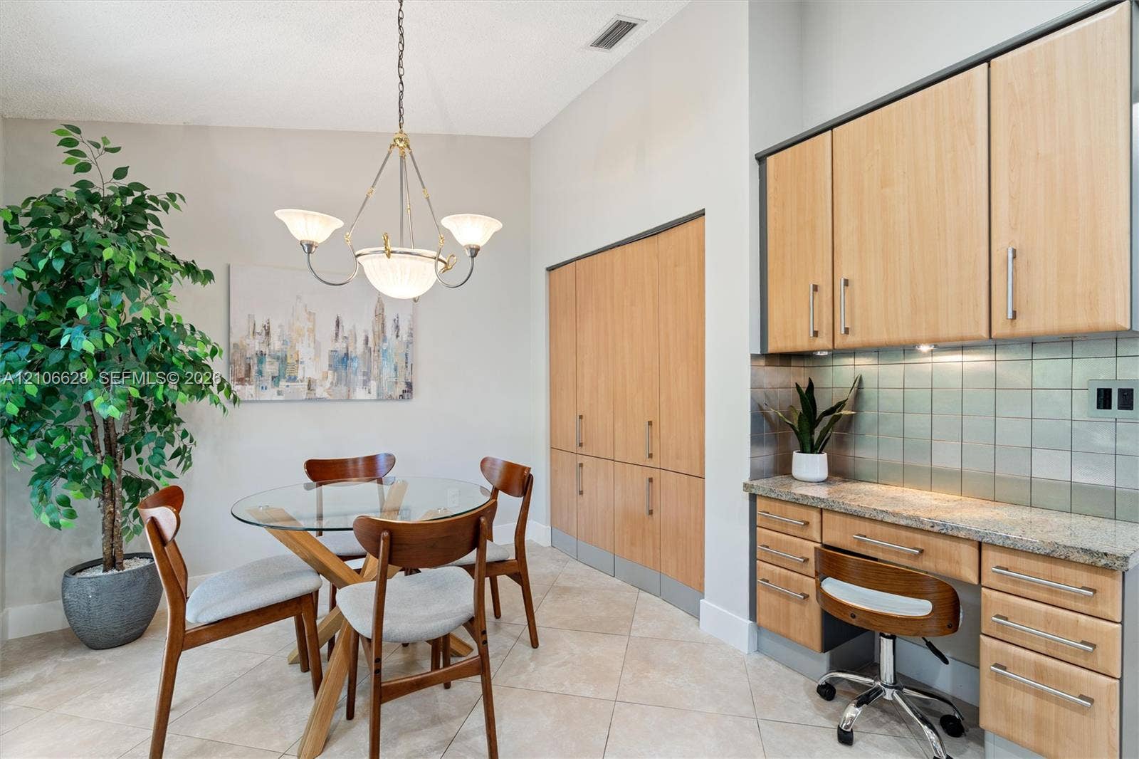 7259 Via Palomar, Boca Raton, FL 33433 Built-in light-tone cabinetry, stone countertop workspace, tiled backsplash, and decorative multi-arm chandelier